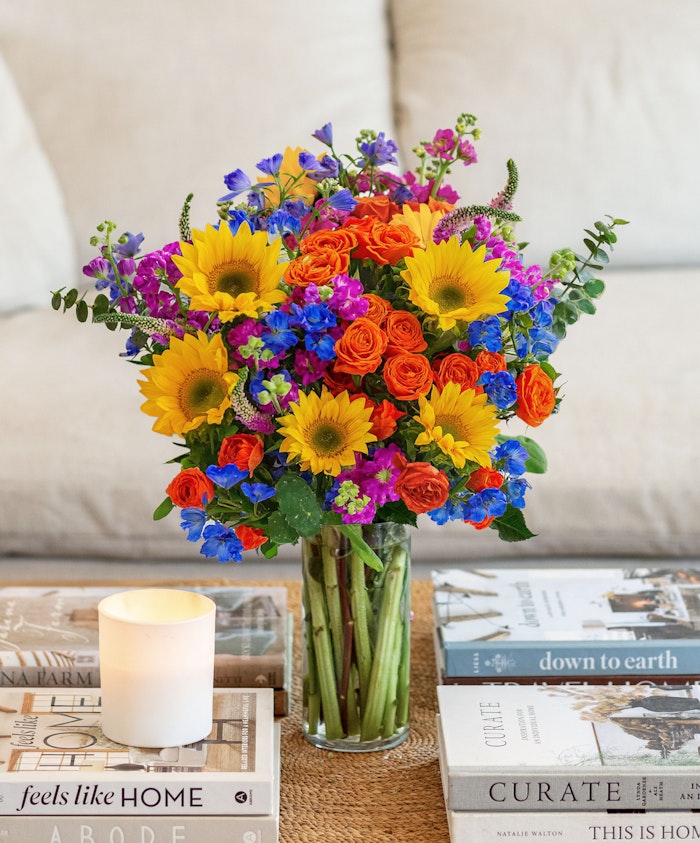 Vibrant floral arrangement featuring sunflowers, roses, and colorful blooms in a vase.