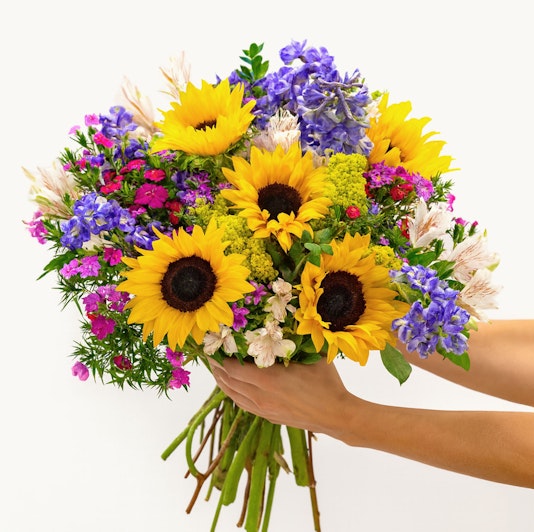 Vibrant bouquet featuring sunflowers, purple flowers, and pink accents, perfect for celebrations.