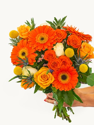 Vibrant bouquet featuring orange gerberas, roses, and yellow accents, perfect for celebrations.