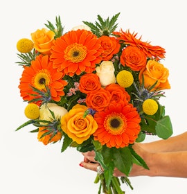 Vibrant bouquet featuring orange gerberas, roses, and yellow accents, perfect for celebrations.