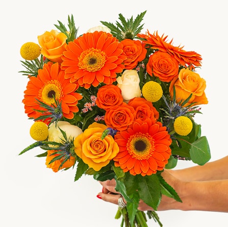 Vibrant bouquet featuring orange gerberas, roses, and yellow accents, perfect for celebrations.