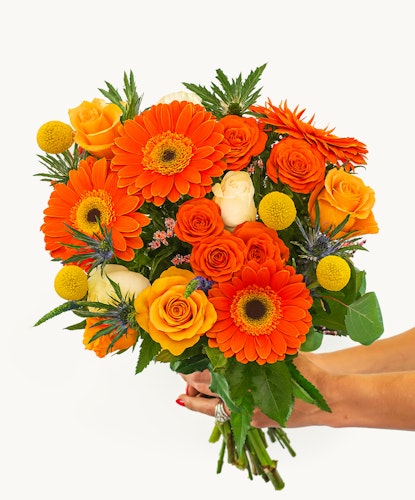 Vibrant bouquet featuring orange gerberas, roses, and yellow accents, perfect for celebrations.