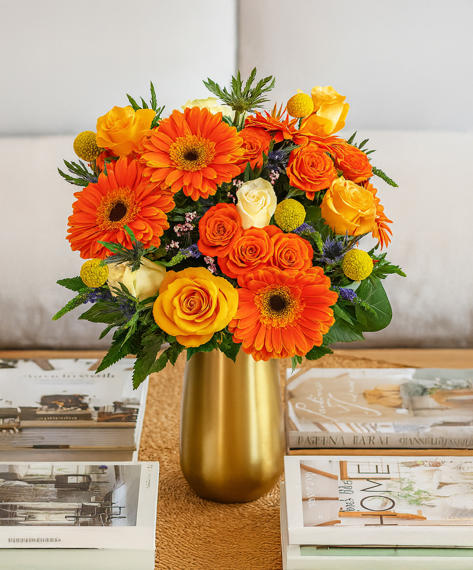 Bright floral arrangement featuring orange gerberas, yellow roses, and greenery in a chic vase.