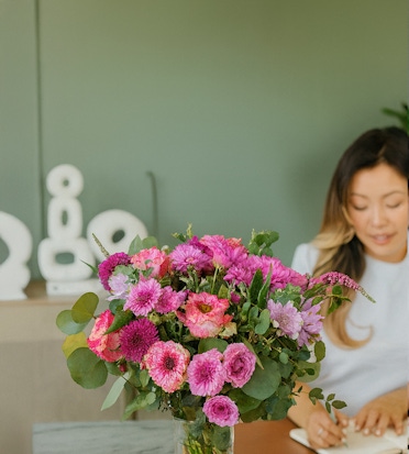A vibrant bouquet of pink flowers with greenery, brightening a serene workspace.