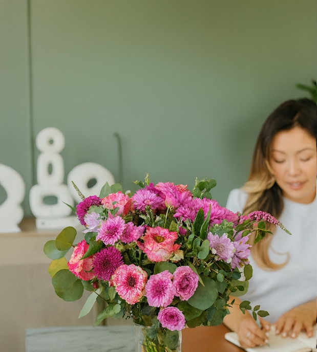 A vibrant bouquet of pink flowers with greenery, brightening a serene workspace.