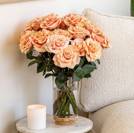A charming bouquet of peach roses in a glass vase, enhancing a cozy living space.