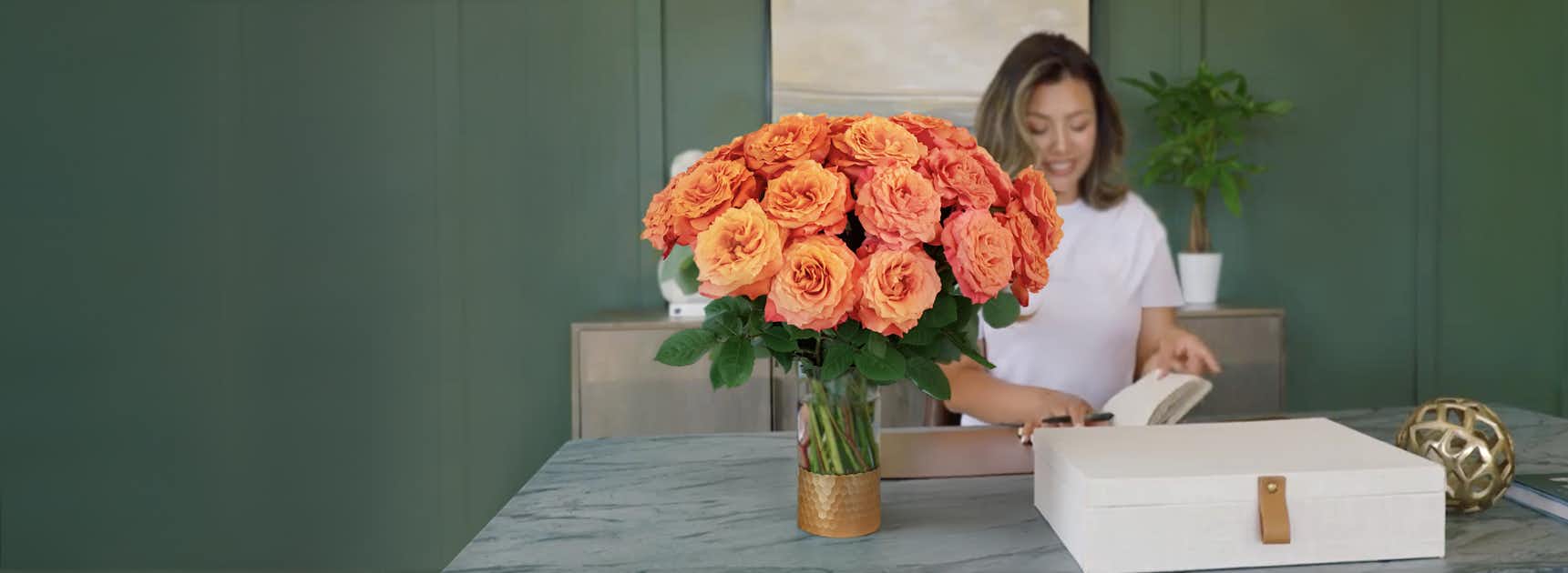 Vibrant orange roses in a chic vase brighten a stylish indoor space, adding elegance.