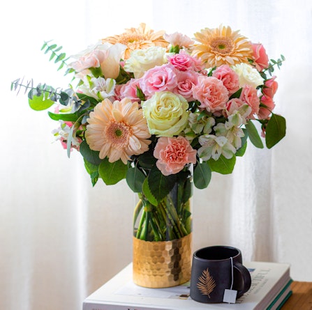 Bright and vibrant floral arrangement with pink roses, gerbera daisies, and lush greenery.
