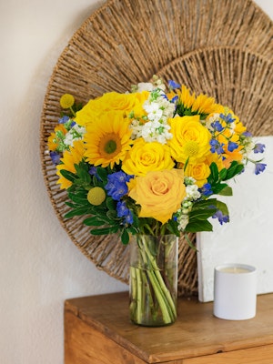 Bright yellow roses and sunflowers in a cheerful vase, perfect for brightening any space.