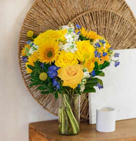 Bright yellow roses and sunflowers in a cheerful vase, perfect for brightening any space.