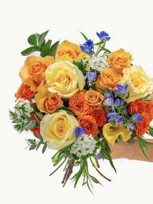 Vibrant bouquet of orange and yellow roses, accented with blue flowers and greenery.