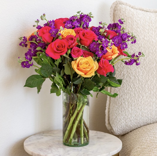 Bright and colorful bouquet featuring red, orange, and purple flowers in a glass vase.