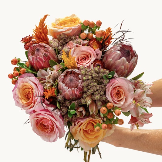 Vibrant floral bouquet featuring pink roses and striking proteas, perfect for celebrations.