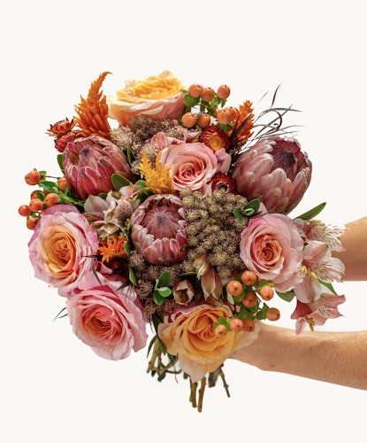 Vibrant floral bouquet featuring pink roses and striking proteas, perfect for celebrations.