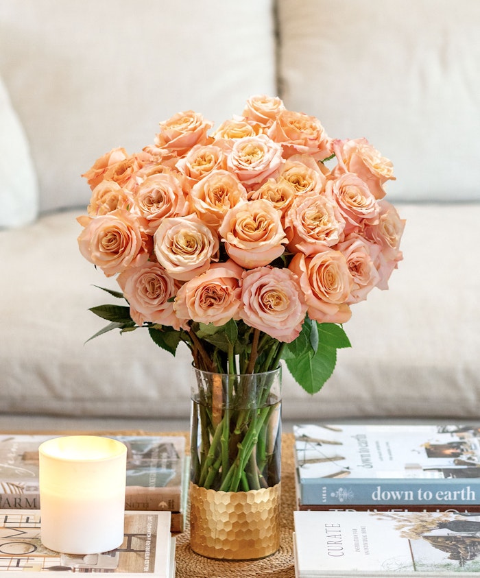 A stunning bouquet of peach roses elegantly arranged in a glass vase on a coffee table.