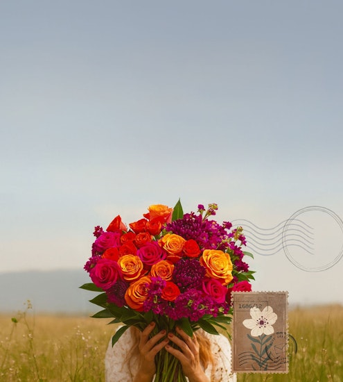 Vibrant floral bouquet of pink, orange, and purple roses held against a serene backdrop.
