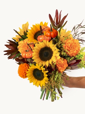 Vibrant floral bouquet featuring sunflowers, marigolds, and miniature pumpkins in autumn hues.