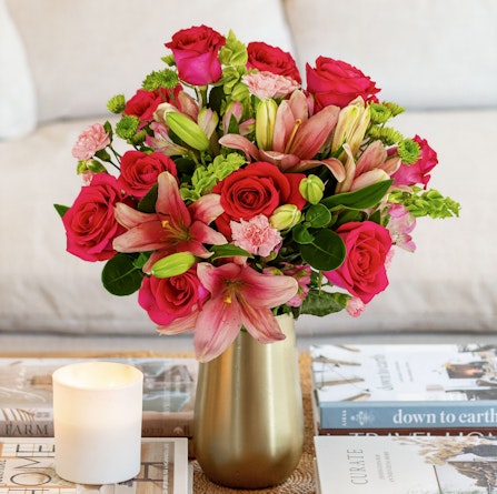 Vibrant floral arrangement with pink roses and lilies in a chic gold vase, perfect for decor.