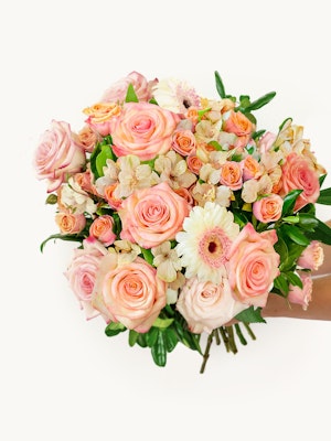 Vibrant bouquet of pink roses, daisies, and delicate flowers in a charming arrangement.