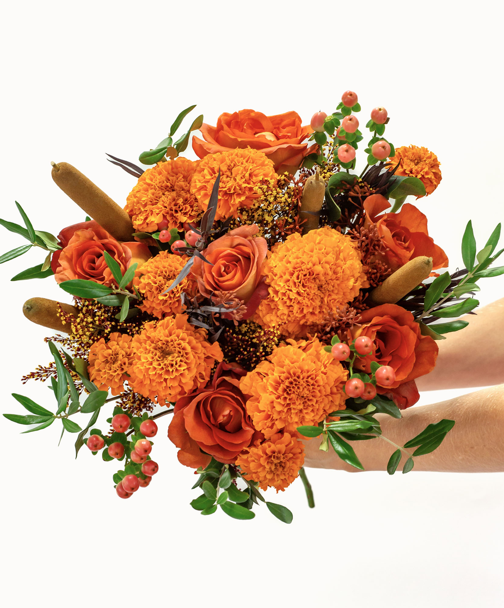 Vibrant bouquet of orange roses and marigolds, accented with lush greenery and berries.