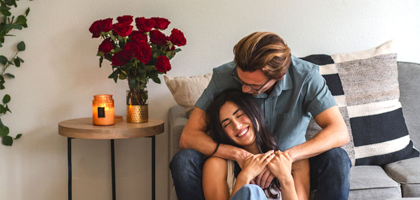 Couple enjoying a cozy moment together amidst a romantic setting with red roses.