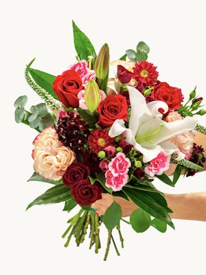 Vibrant bouquet featuring red roses, pink lilies, and assorted seasonal flowers, beautifully arranged.