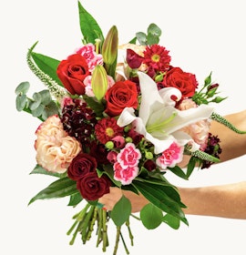 Vibrant bouquet featuring red roses, pink lilies, and assorted seasonal flowers, beautifully arranged.