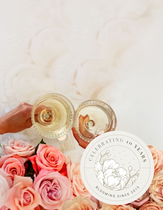 Elegant champagne flutes toasting over a vibrant rose bouquet, celebrating a milestone anniversary.