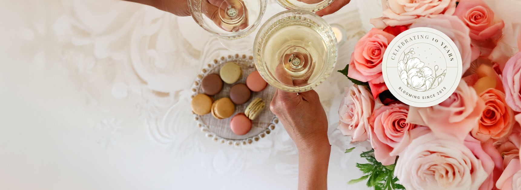 Elegant celebration with sparkling glasses, macarons, and a lovely rose bouquet.