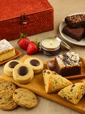 A tempting assortment of baked goods, strawberries, and a scented candle on a table.
