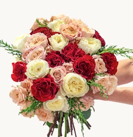 Luxurious floral bouquet featuring red, pink, and white roses with lush greenery accents.