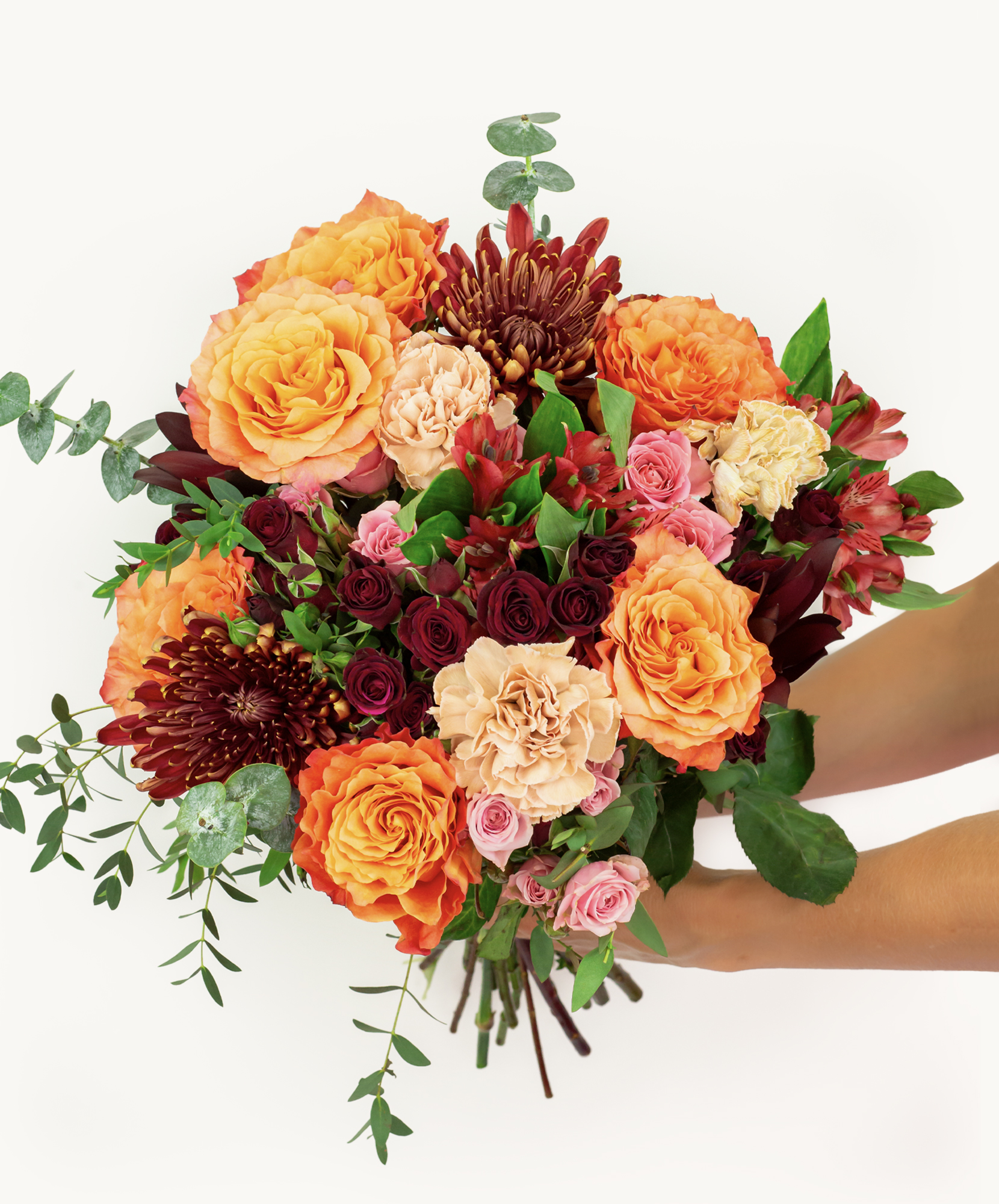 Vibrant floral bouquet featuring orange roses, pink blooms, and lush green leaves.