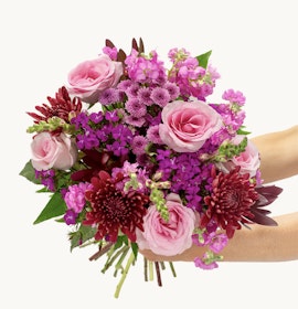 Vibrant floral bouquet featuring pink roses, purple blooms, and lush greenery, ideal for gifting.
