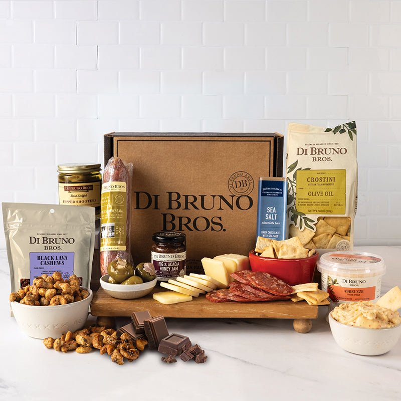 Gourmet snack box includes cheeses, meats, olives, and chocolates for a delightful treat.