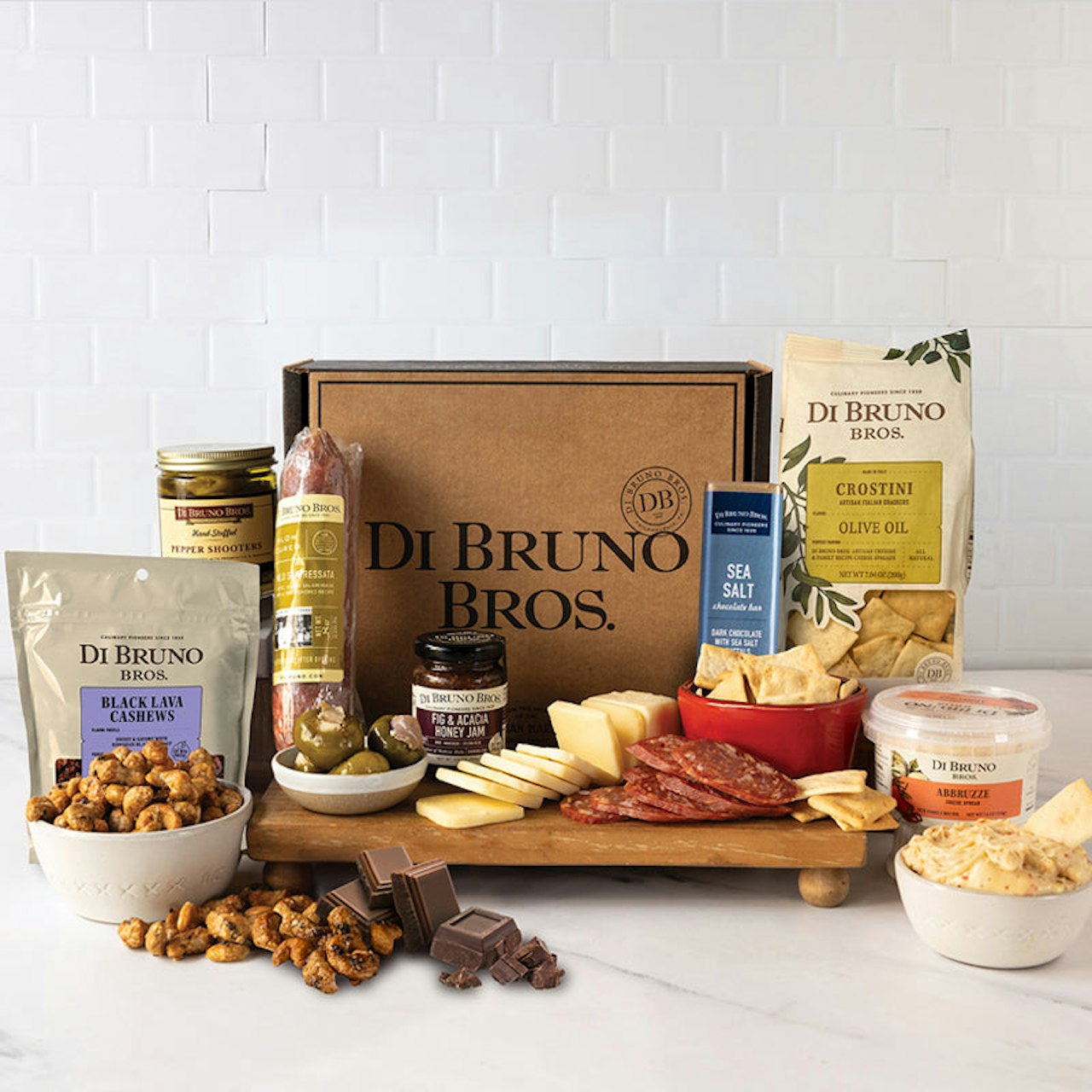 Gourmet snack box includes cheeses, meats, olives, and chocolates for a delightful treat.
