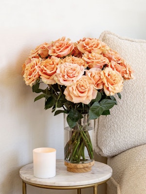 Elegant bouquet of peach roses in a glass vase, enhancing a cozy home decor setting.