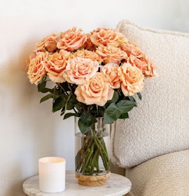 Elegant bouquet of peach roses in a glass vase, enhancing a cozy home decor setting.