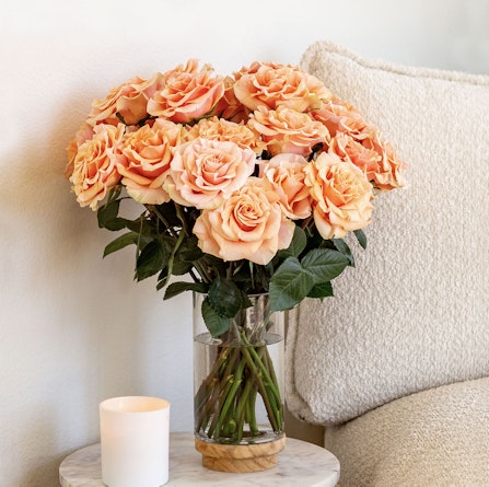 Elegant bouquet of peach roses in a glass vase, enhancing a cozy home decor setting.
