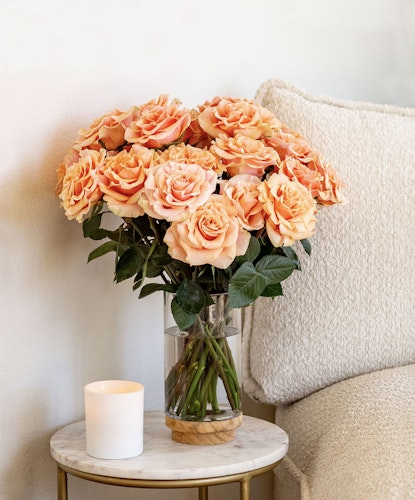 Elegant bouquet of peach roses in a glass vase, enhancing a cozy home decor setting.