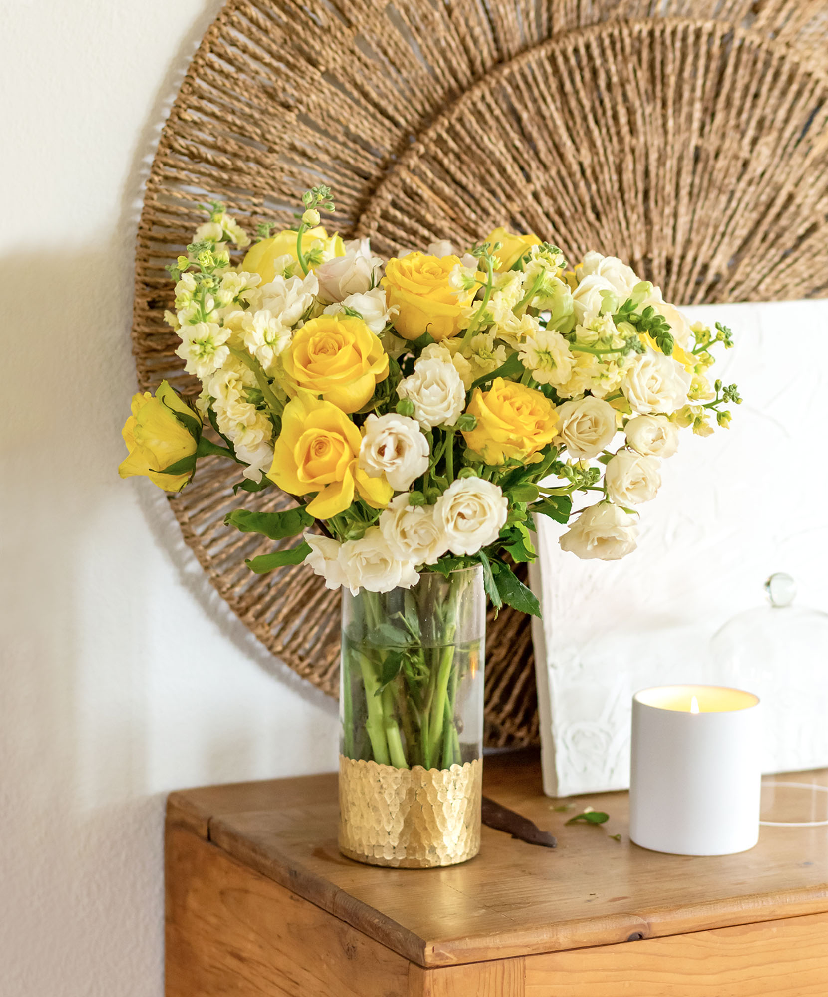 Bright yellow and white roses beautifully arranged in a glass vase, enhancing decor with elegance.