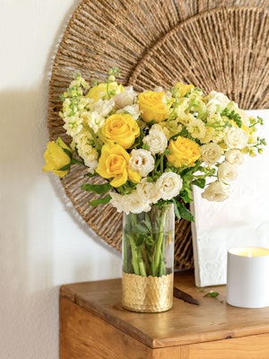 Bright yellow and white roses beautifully arranged in a glass vase, enhancing decor with elegance.