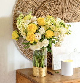 Bright yellow and white roses beautifully arranged in a glass vase, enhancing decor with elegance.