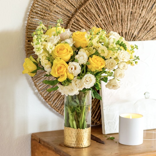 Bright yellow and white roses beautifully arranged in a glass vase, enhancing decor with elegance.