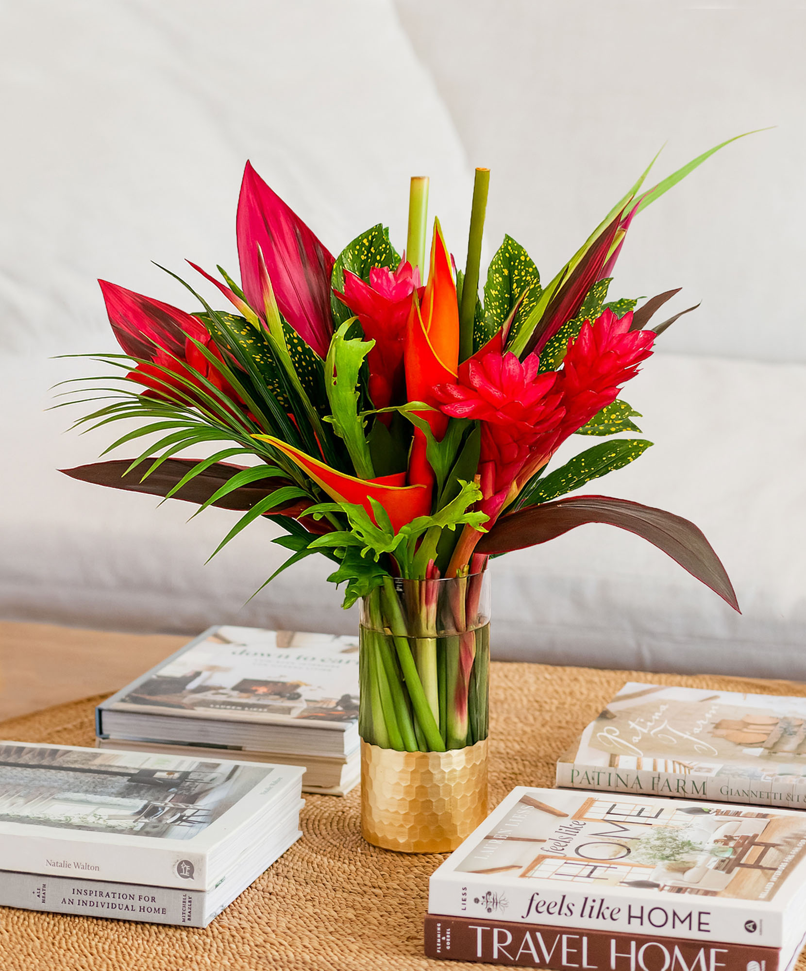 Vibrant tropical flower arrangement with red ginger, anthurium, and lush foliage.