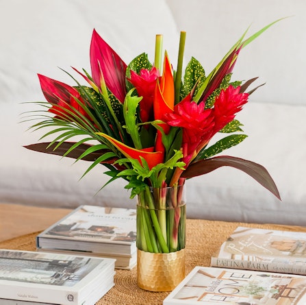 Vibrant tropical flower arrangement featuring red ginger and heliconia in a stylish vase.