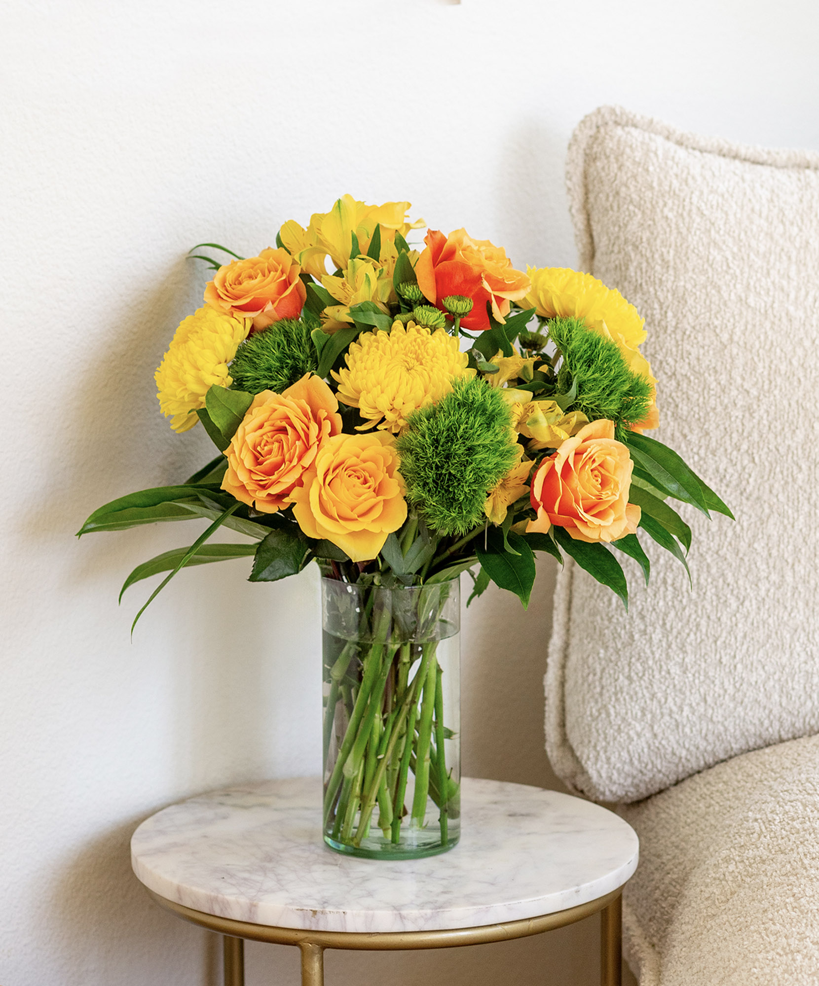 Vibrant yellow and orange floral arrangement in a glass vase, perfect for brightening up any space.