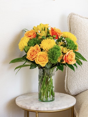 Vibrant yellow and orange floral arrangement in a glass vase, perfect for brightening up any space.