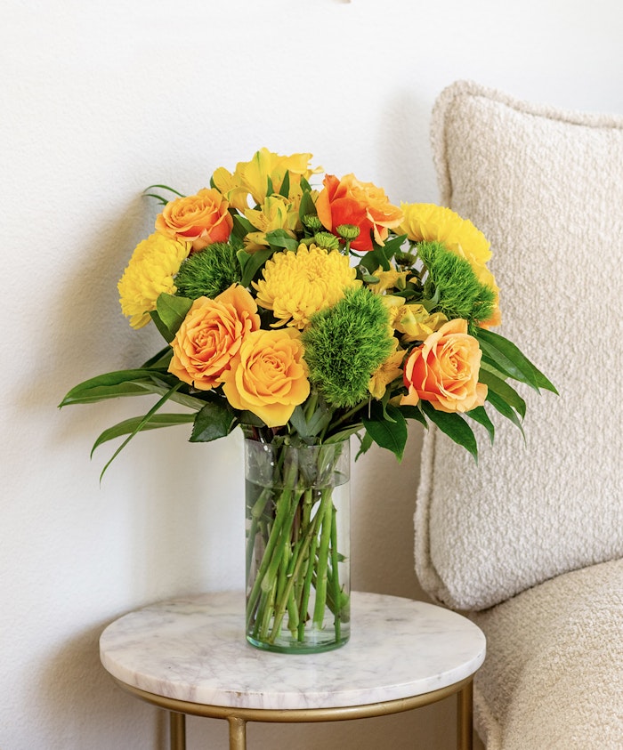 Vibrant yellow and orange floral arrangement in a glass vase, perfect for brightening up any space.