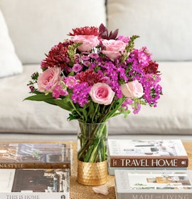 Vibrant floral arrangement featuring pink roses and mixed blooms on a coffee table.