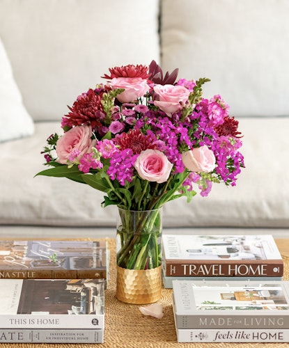 Vibrant floral arrangement with pink roses and purple blooms in a stylish vase, enhancing decor.